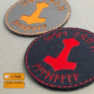 May include: Two round embroidered patches with a hammer symbol and runes. The top patch is gray with orange stitching and an orange hammer. The bottom patch is black with red stitching and a red hammer.
