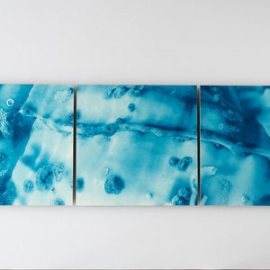 May include: A three-piece abstract art print set featuring a blue and white color scheme. The artwork has a marbled, textured look with a swirling pattern.