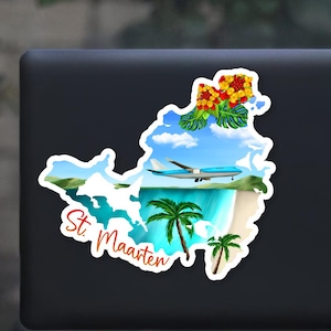 May include: A white sticker with a colorful illustration of the island of St. Maarten. The island is surrounded by blue water and palm trees. A blue airplane flies over the island. The text "St. Maarten" is written in red and orange.