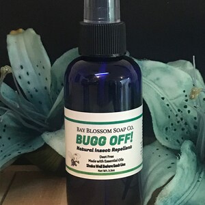 May include: A dark blue spray bottle of "Bugg Off!" natural insect repellent. The label reads "Bay Blossom Soap Co." and includes the text "Deet Free" and "Made with Essential Oils." The bottle contains 3.5 oz of product.