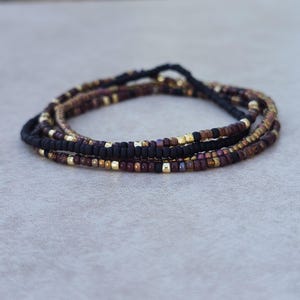 May include: A multi-strand beaded bracelet with black, brown, and gold beads.