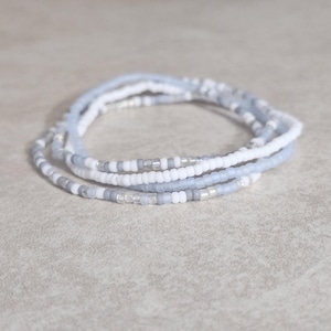 May include: A layered bracelet made of small white and light blue beads.