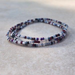 May include: A multi-strand beaded bracelet with white, gray, black, and burgundy beads.