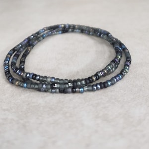 May include: A multi-strand beaded bracelet with iridescent blue and black beads.