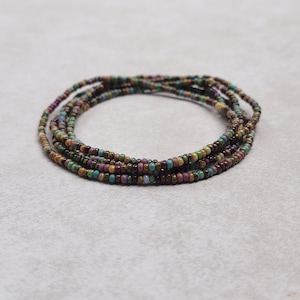 May include: Multi-colored beaded bracelet with a variety of brown, green, and purple beads.