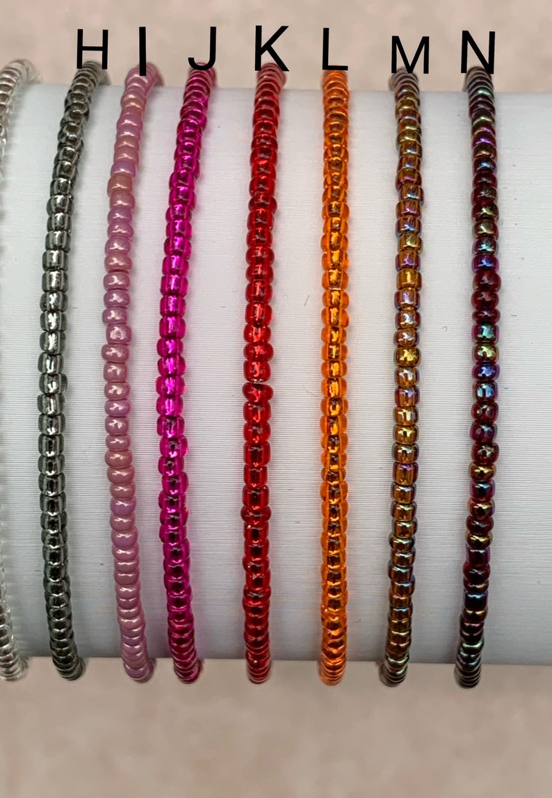 May include: Eight strands of colorful beaded bracelets in various colors, including silver, pink, magenta, red, orange, and iridescent.