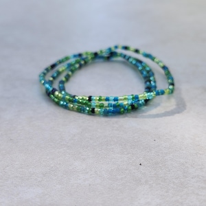 May include: A multi-strand beaded bracelet with green, blue, and black beads.