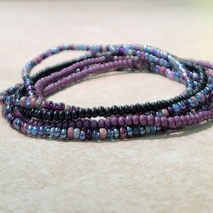 May include: A multi-strand beaded bracelet with purple, black, and iridescent blue beads.