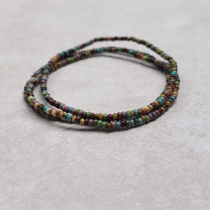 May include: A multi-strand beaded bracelet with brown, green, and purple beads.