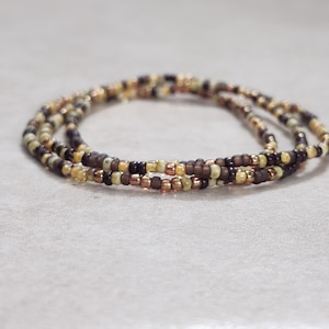 May include: A multi-strand beaded bracelet with brown, beige, and gold beads.