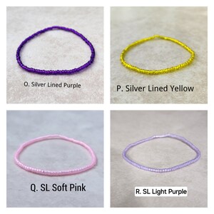 May include: Four beaded bracelets in different colors: purple, yellow, pink, and light purple. Each bracelet has a silver lining.