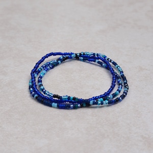 May include: A multi-strand beaded necklace with blue, teal, and black beads.