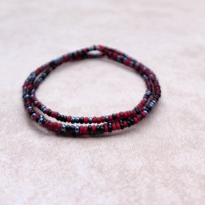 May include: A multi-strand beaded necklace with red, black, and blue beads.
