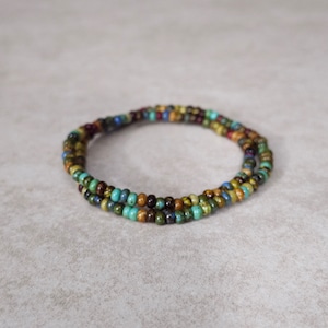 May include: A multi-colored beaded bracelet with brown, green, blue, and red beads.