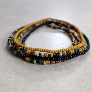 May include: A multi-strand beaded necklace with black, yellow, and brown beads.
