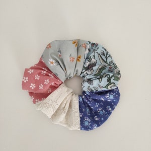 Pu&ograve; includere: Un elastico per capelli in tessuto multicolore con un motivo floreale. Lo scrunchie &egrave; realizzato con cinque tessuti diversi, ognuno con un diverso motivo floreale. Lo scrunchie ha una forma circolare ed &egrave; legato con un nodo.