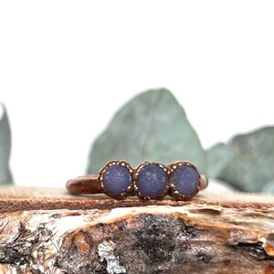 May include: A copper ring with three purple stones set in the band.