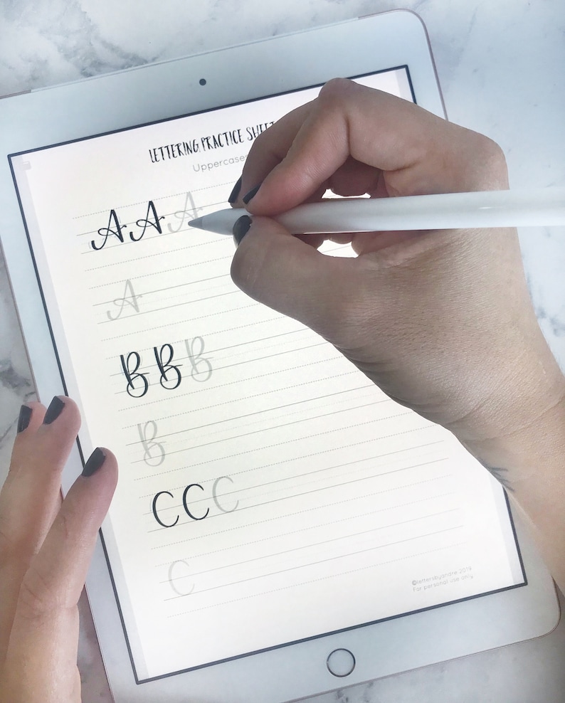 May include: A digital tablet screen displaying a lettering practice sheet with uppercase letters A, B, and C written in cursive. The letters are written in black ink on a white background with gray lines.