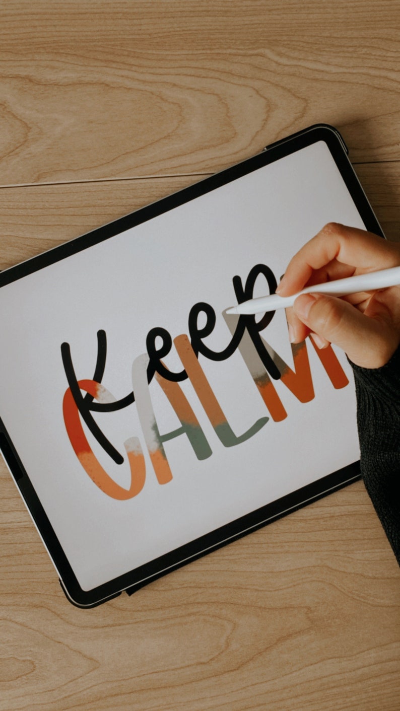 May include: A hand uses a stylus to draw the words "Keep Calm" on a white digital tablet. The words are in black and are outlined in orange, green, and white.