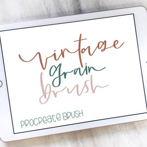 May include: A white tablet screen displaying the text "vintage grain brush" in brown, green, and pink lettering. The text "Procreate Brush" is displayed in green at the bottom of the screen.