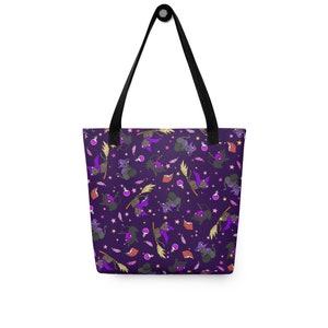 Puede incluir: Bolsa de tela morada con un patrón repetido de gatos negros con sombreros de bruja y montando escobas. Los gatos sostienen libros y frascos de pociones. También hay estrellas y plumas en el patrón.