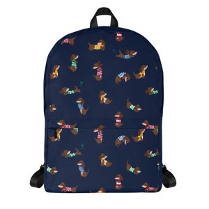 May include: A navy blue backpack with a repeating pattern of brown dachshunds wearing colorful sweaters. The dachshunds are in various poses, including sitting, standing, and lying down.