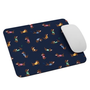 May include: A navy blue mouse pad with a repeating pattern of brown dachshunds wearing colorful sweaters. The dachshunds are in various poses, some are sitting, some are standing, and some are running.