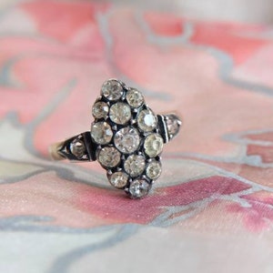 Op de afbeelding: Een zilveren ring met een cluster van heldere stenen in een marquise-vorm.