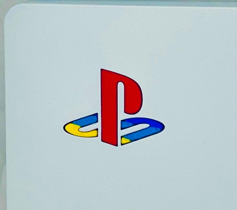 May include: A white PlayStation console with the PlayStation logo in red, blue and yellow.