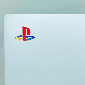 May include: A white surface with the PlayStation logo in red, blue, and yellow.