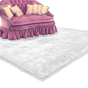 May include: A white fluffy rug with a pink tufted sofa with pillows on top of it.