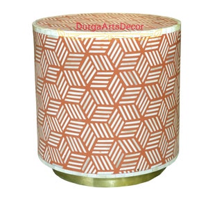 May include: A round, orange and white side table with a geometric pattern. The table has a brass base.