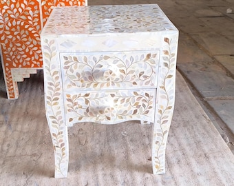 Mesita de noche con incrustaciones de nácar blanco y diseño floral.
