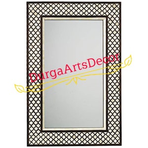 Puede incluir: Un espejo rectangular con un marco decorativo de incrustaciones de hueso. El marco presenta un patrón geométrico en blanco y negro.