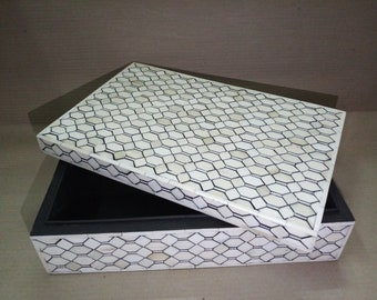 May include: A white bone inlay box with a black geometric pattern on the lid and sides. The box is open and the inside is black.