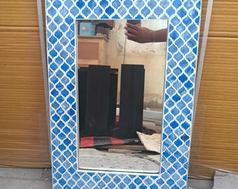 May include: Rectangular mirror with a blue and white patterned frame. The frame has a repeating quatrefoil design in shades of blue against a white background. The mirror reflects the surrounding environment.