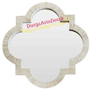 Puede incluir: Un espejo de incrustaciones de hueso blanco con forma de trébol de cuatro hojas. El espejo tiene un borde biselado y un marco de incrustaciones de hueso blanco. El espejo tiene un diámetro de 45,7 cm. El texto "DurgaArtsDecor" es visible en la parte superior central del espejo.