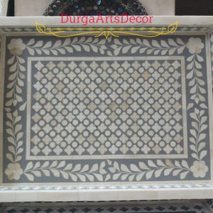A grey and white bone inlay serving tray with a floral design and a geometric pattern. The tray has a white border and two handles on the sides. "DurgArtsDecor" is written in gold lettering on the top of the tray.