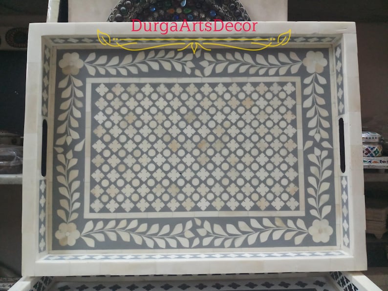 A grey and white bone inlay serving tray with a floral design and a geometric pattern. The tray has a white border and two handles on the sides. "DurgArtsDecor" is written in gold lettering on the top of the tray.