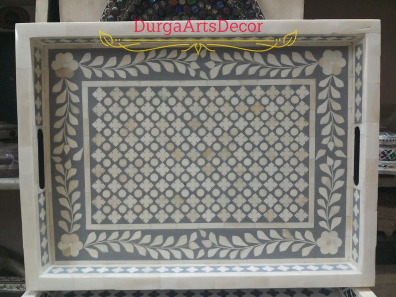 A grey and white bone inlay serving tray with a floral design and a geometric pattern. The tray has a white border and two handles on the sides. "DurgArtsDecor" is written in gold lettering on the top of the tray.