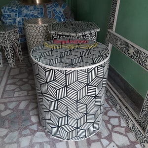 May include: A round side table with a black and white geometric pattern made of bone inlay. The table is cylindrical in shape and measures approximately 61 cm in diameter.