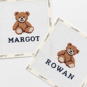 Puede incluir: Dos lienzos cuadrados de punto de cruz con un diseño de oso de peluche marrón. Un lienzo muestra el nombre MARGOT en azul oscuro, mientras que el otro muestra el nombre ROWAN en azul oscuro. Los bordes están rematados con cinta color crema.