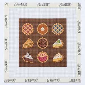 May include: A square needlepoint canvas featuring a brown background with a grid of nine pie illustrations, including whole pies and slices. The white border is printed with the repeating text Birch NDLPT along all four edges of the canvas.