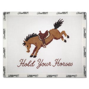May include: A white needlepoint canvas featuring a brown bucking horse with a dark saddle. The text "Hold Your Horses" is stitched in dark red below the horse. The border is printed with the repeating text "Birch NDLPT".