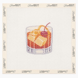 Könnte beinhalten: Eine Stickvorlage mit einem im Kreuzstich gestickten Old-Fashioned-Cocktail in einem Glas mit Eiswürfeln, einer Orangenschale und einer roten Kirsche. Der Text BirchNDLPT ist wiederholt entlang des weißen Gitterrandes der quadratischen Leinwand gedruckt.