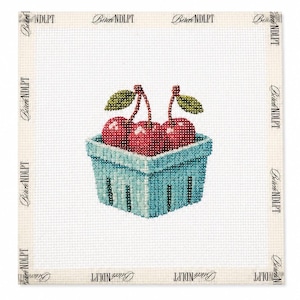 May include: A needlepoint canvas featuring a square light blue berry basket filled with three bright red cherries, each with a green stem and leaf. The canvas has a white grid background and the text Birch NDLPT printed along the border edges.
