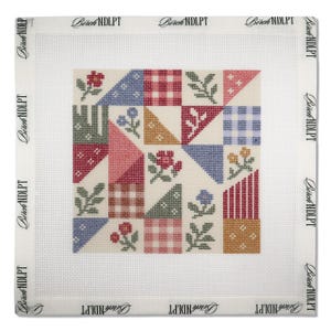 May include: A square needlepoint canvas featuring a patchwork quilt design with various geometric shapes, floral motifs, and checkered patterns in red, blue, green, and yellow. The border is printed with the text Birch NDLPT repeatedly.