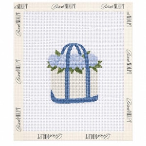 Puede incluir: Un lienzo de punto de aguja con un monograma azul de la letra J adornado con flores de color azul claro similares a las hortensias y hojas verdes. La tela de malla blanca tiene el logo Birch NDLPT repetido en los bordes color crema.