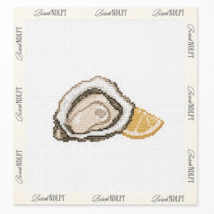 May include: A cross-stitch pattern on white fabric featuring an open oyster shell with a beige interior and a yellow lemon wedge. The text Birch NDLPT is printed repeatedly along the white border of the square fabric piece.