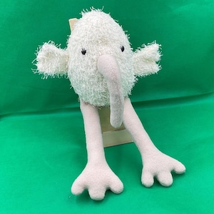 Puede incluir: Juguete de peluche blanco con una nariz larga de color rosa y patas largas de color rosa. El juguete tiene ojos negros y un cuerpo blanco esponjoso.